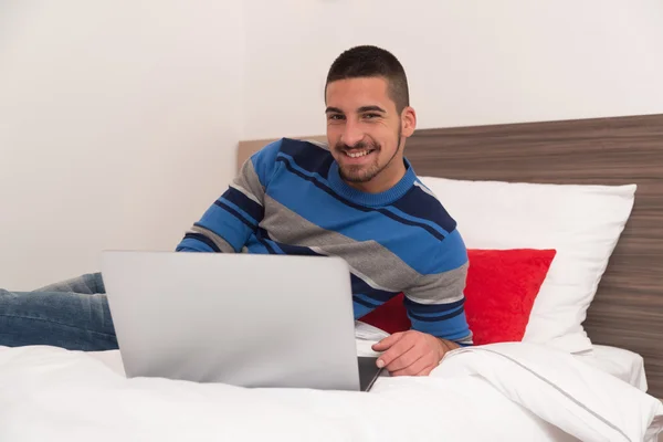 Étudiant heureux sur le lit en utilisant un ordinateur portable — Photo