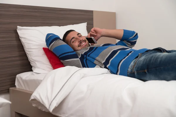 Feliz estudiante masculino en el dormitorio en el teléfono —  Fotos de Stock