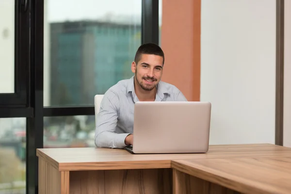 Estudante masculino feliz na biblioteca com laptop — Fotografia de Stock