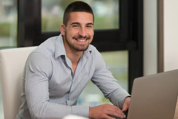 Glücklicher Student in der Bibliothek mit seinem Laptop — Stockfoto