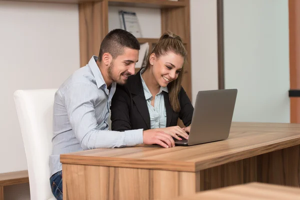 Estudantes felizes na biblioteca usando seu laptop — Fotografia de Stock