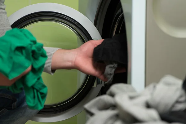 Jovem colocando um pano na máquina de lavar roupa — Fotografia de Stock