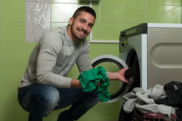 Jeune homme chargeant la machine à laver dans la chambre — Photo