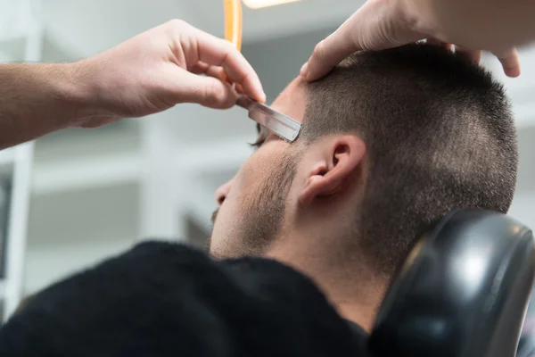 Peluquería afeitar la barbilla del hombre con una navaja de afeitar recta — Foto de Stock