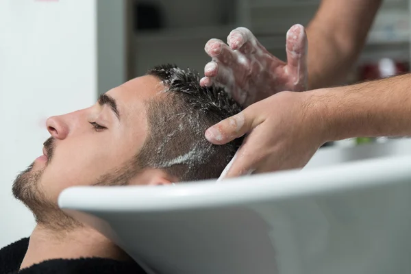 Uomo sorridente avendo i capelli lavati dal parrucchiere — Foto Stock