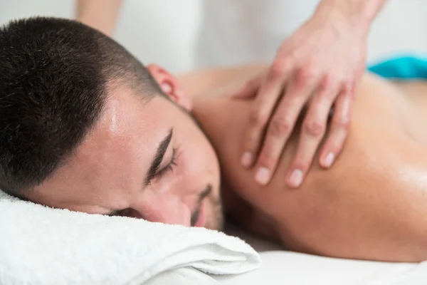 Hombre guapo recibiendo un masaje de espalda acostado — Foto de Stock