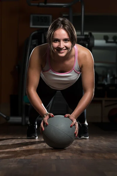 Junge Frau übt Liegestütze auf Medizinball — Stockfoto