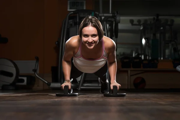 Mujer joven haciendo ejercicio Push Ups en el suelo — Foto de Stock