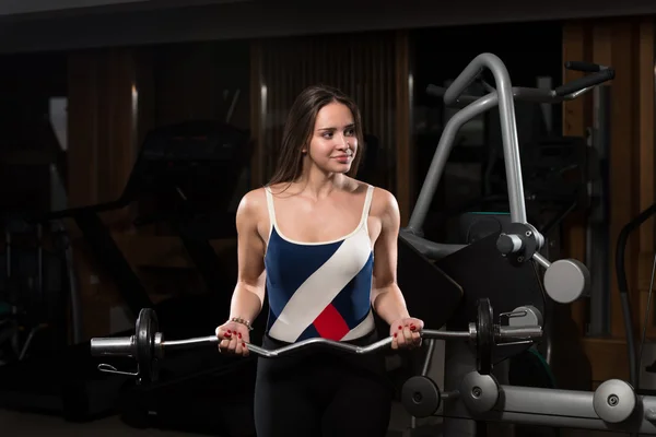 Jovem mulher exercendo bíceps com Barbell — Fotografia de Stock