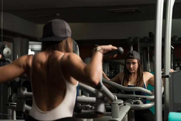 Jovem do sexo feminino fazendo exercícios nas costas no ginásio — Fotografia de Stock