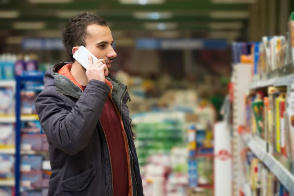 Bell'uomo sul cellulare al supermercato — Foto Stock