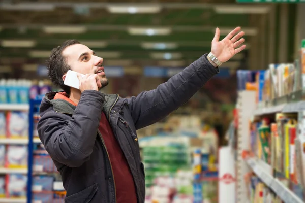 Przystojny mężczyzna na telefon komórkowy w supermarkecie — Zdjęcie stockowe