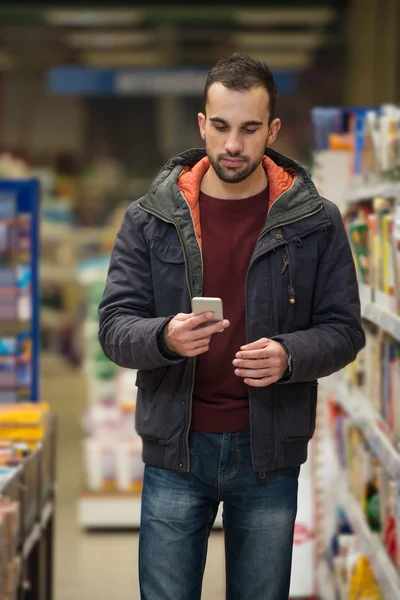 Mężczyzna patrząc na telefon komórkowy w centrum handlowym — Zdjęcie stockowe