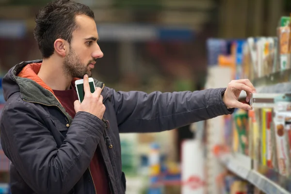在超市购物时使用手机的人 — 图库照片