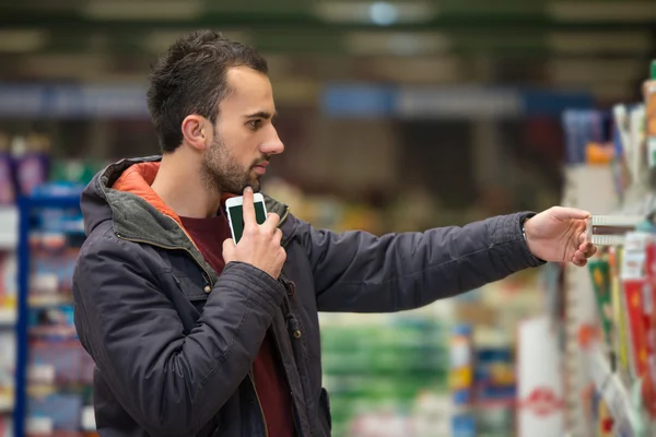 Mand kigger på mobiltelefon i indkøbscenter - Stock-foto