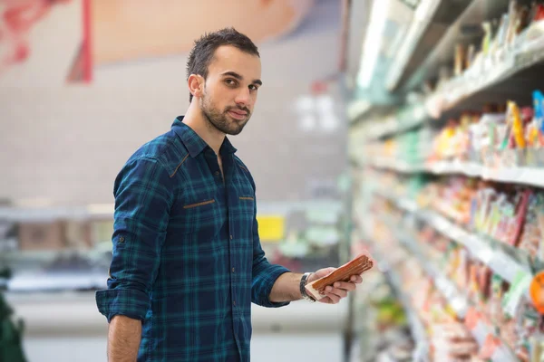 Bir bakkal süpermarket alışveriş yakışıklı genç — Stok fotoğraf