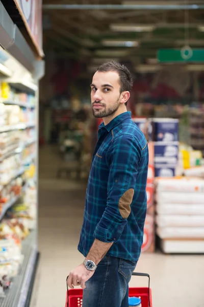 Schöner junger Mann beim Einkaufen in einem Supermarkt — Stockfoto