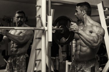 Bodybuilder Putting Weights On Bar In Gym