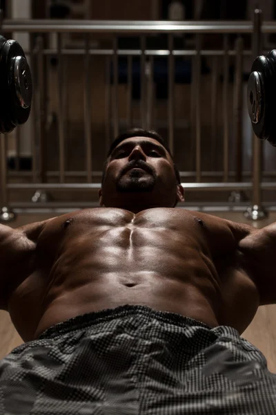 Culturista haciendo ejercicio para el pecho con sombrillas — Foto de Stock