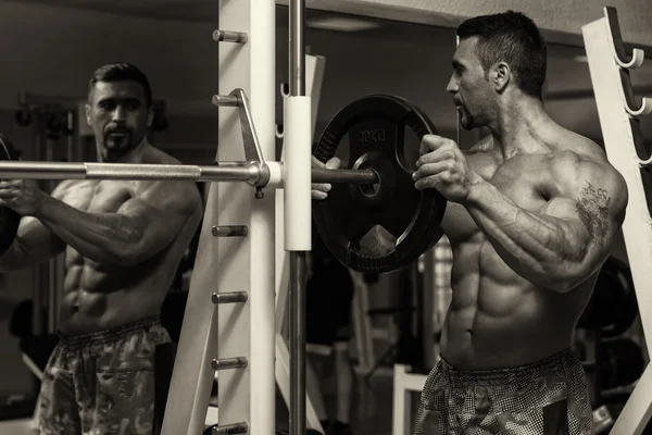 Culturista mettendo pesi su bar in palestra — Foto Stock