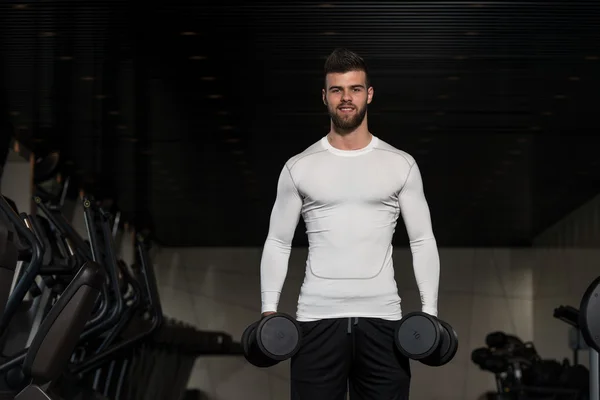 Hombre guapo ejercitando bíceps con sombrillas — Foto de Stock