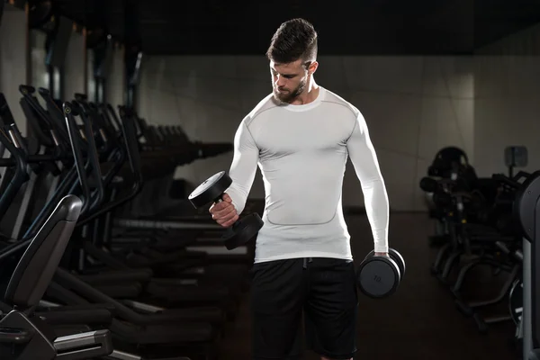 Jovem masculino fazendo exercícios de bíceps no ginásio — Fotografia de Stock