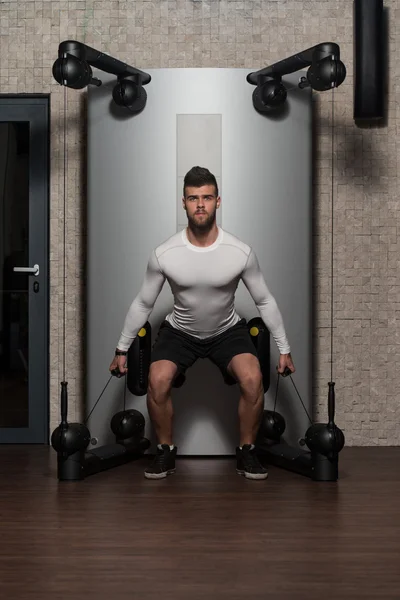 Jovem masculino fazendo exercícios nas costas no ginásio — Fotografia de Stock