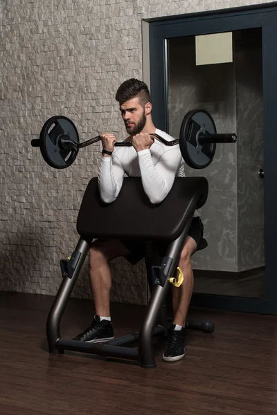 Schöner Mann macht Bizepsübungen im Fitnessstudio — Stockfoto