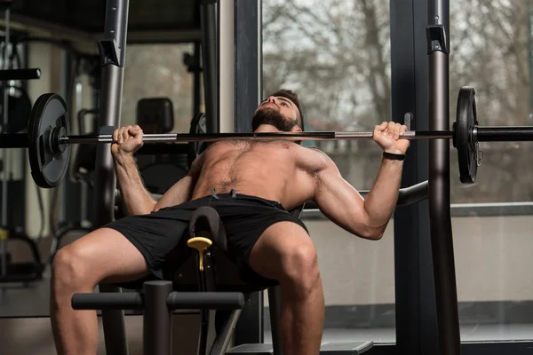 Joven haciendo ejercicio en el pecho con la barra — Foto de Stock