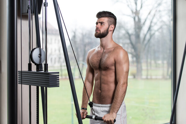 Young Man Exercising Triceps On Machine
