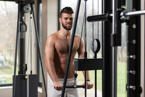 Jovem homem exercitando tríceps na máquina — Fotografia de Stock
