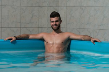 Kollarını havuzu kenarında oturan adam