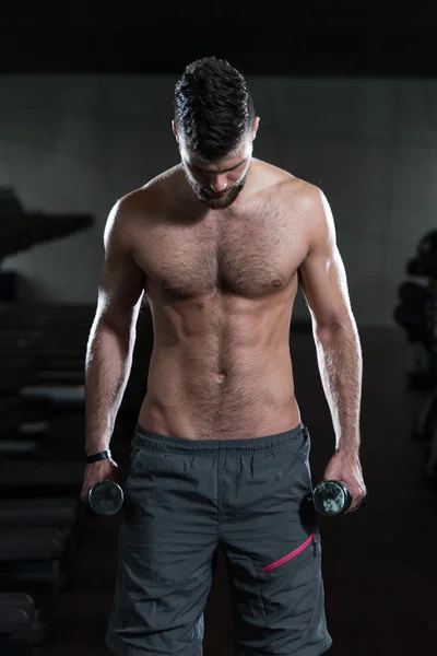 Jovem masculino fazendo exercícios de bíceps no ginásio — Fotografia de Stock