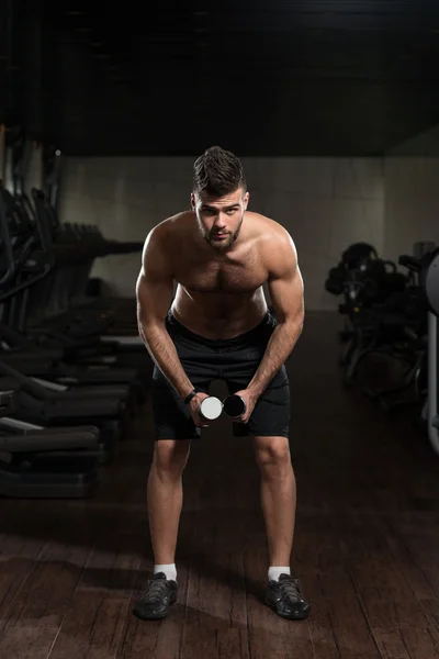 Giovane uomo che esercita le spalle con manubri — Foto Stock