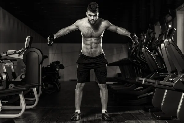 Hombre joven haciendo ejercicio de hombros con sombrillas — Foto de Stock