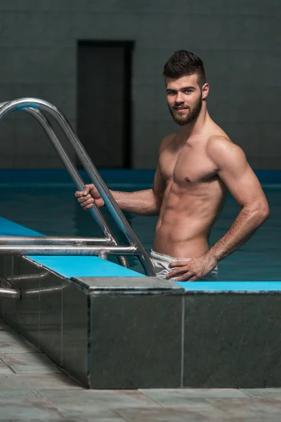 Jovem olhando o homem machista na piscina interior do hotel — Fotografia de Stock