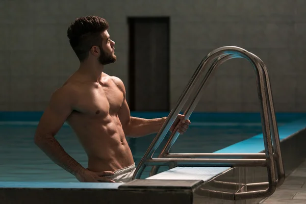 Jovem olhando o homem machista na piscina interior do hotel — Fotografia de Stock