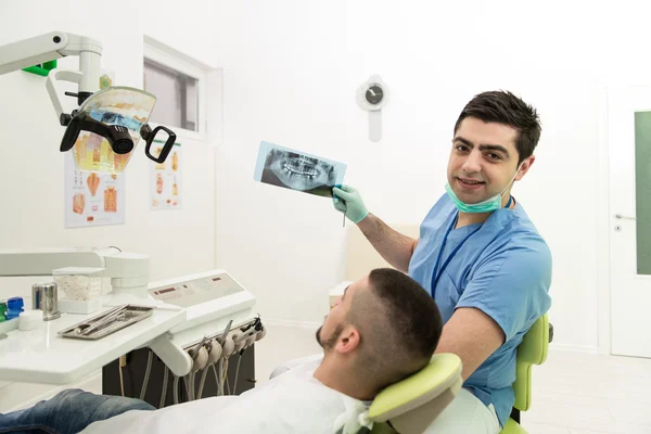 Dentista sosteniendo rayos X y examinando paciente blanco —  Fotos de Stock