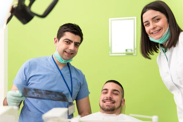 Dentista sosteniendo rayos X y examinando paciente blanco — Foto de Stock