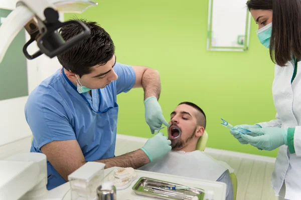 Dentiste soignant un patient de sexe masculin — Photo