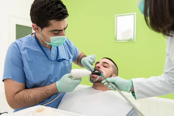 Zahnarzt heilt einen männlichen Patienten — Stockfoto