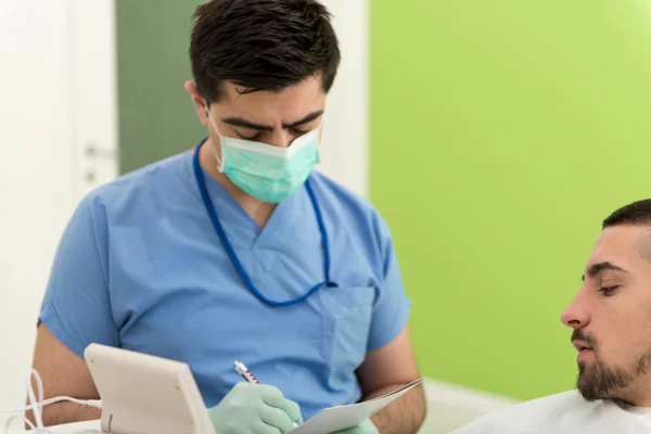 Tandarts schrijft op de patiënt persoonlijke kaartgegevens — Stockfoto