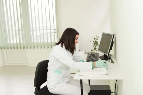 Asistente de dentista escribe algunas notas en libro médico — Foto de Stock