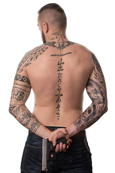 Bakifrån av tillbaka tatuerade mannen med pistolen — Stockfoto