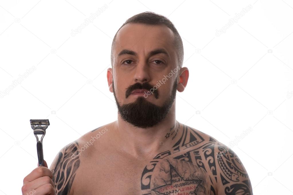 Tattooed Man Styling Beard Holding Disposable Razor