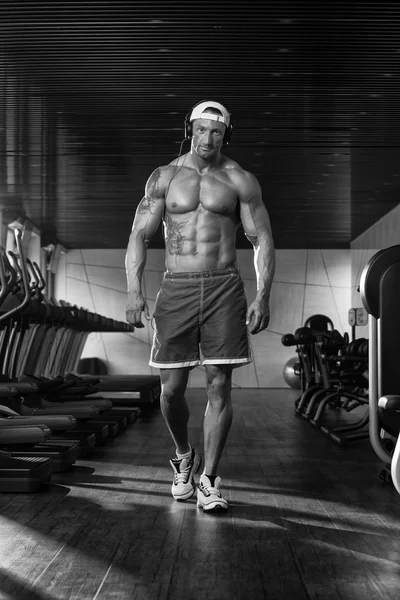 Hombre estético escuchando música en el moderno gimnasio — Foto de Stock