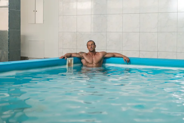 Людина, відпочиваючи руки на краю басейну — стокове фото