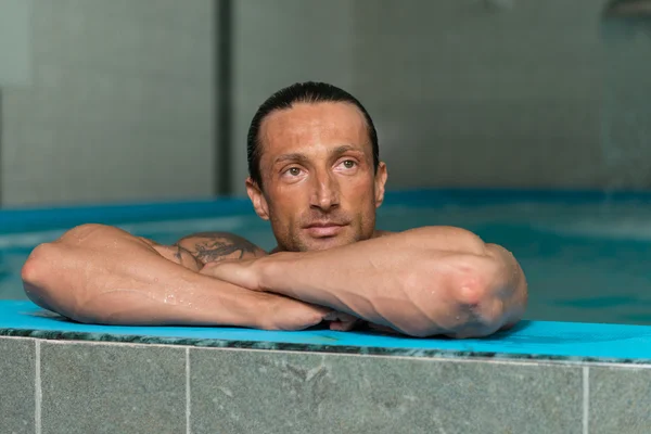 Man Resting His Arms At Edge Of Pool