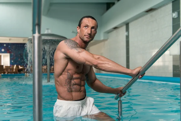 Hombre descansando sus brazos al borde de la piscina — Foto de Stock