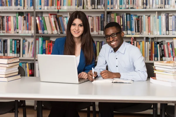 Jovens estudantes usando seu laptop em uma biblioteca — Fotografia de Stock